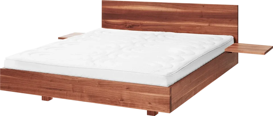 Ein Doppelbett aus rotbraunem Massivholz. Das Bett hat eine schlichte Form und seitlich zwei einfache Brettchen als Nachttische. Im Bett liegen 2 weiße Matratzen ohne Bezug oder Bettzeug.