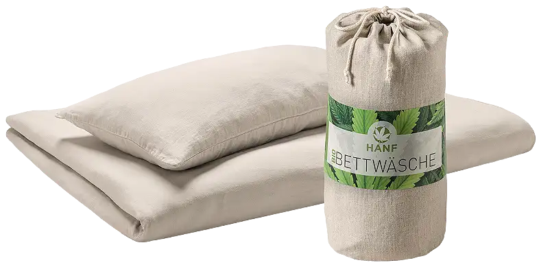 Ein Kissen und eine Bettdecke bezogen mit einem hellbraunen Bezug. Daneben steht ein kleines Säckchen aus dem gleichen Stoff, auf dem Hanf-Bio-Bettwäsche steht